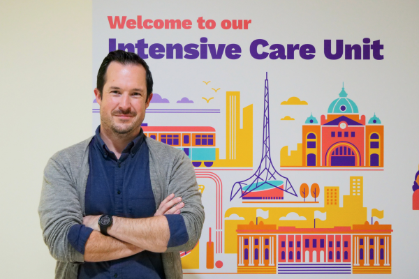 Austin Health's Infectious Diseases Physician Dr Morgan Rose standing in front of sign for Intensive Care Unit